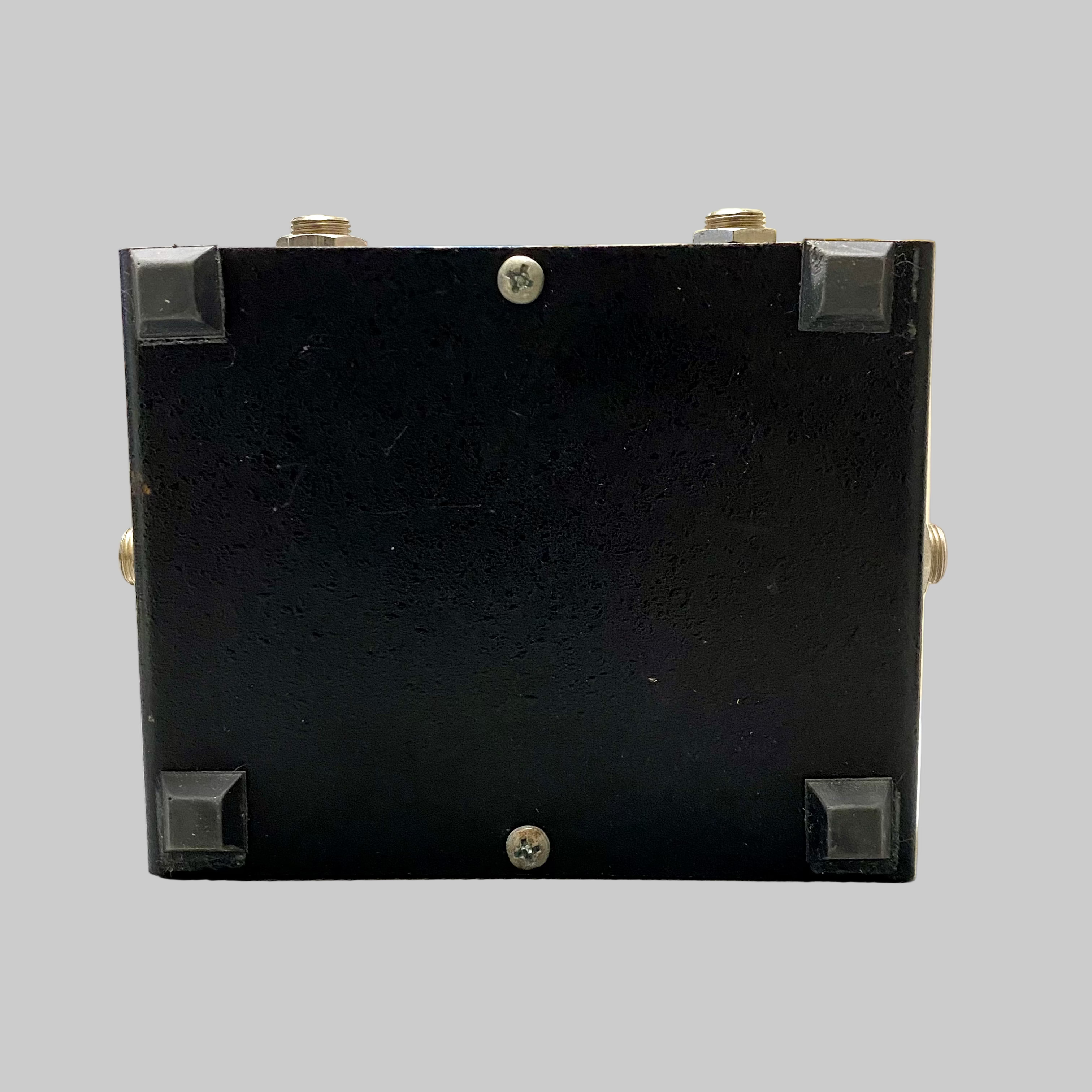 Black rectangular object with screws on a light-colored surface