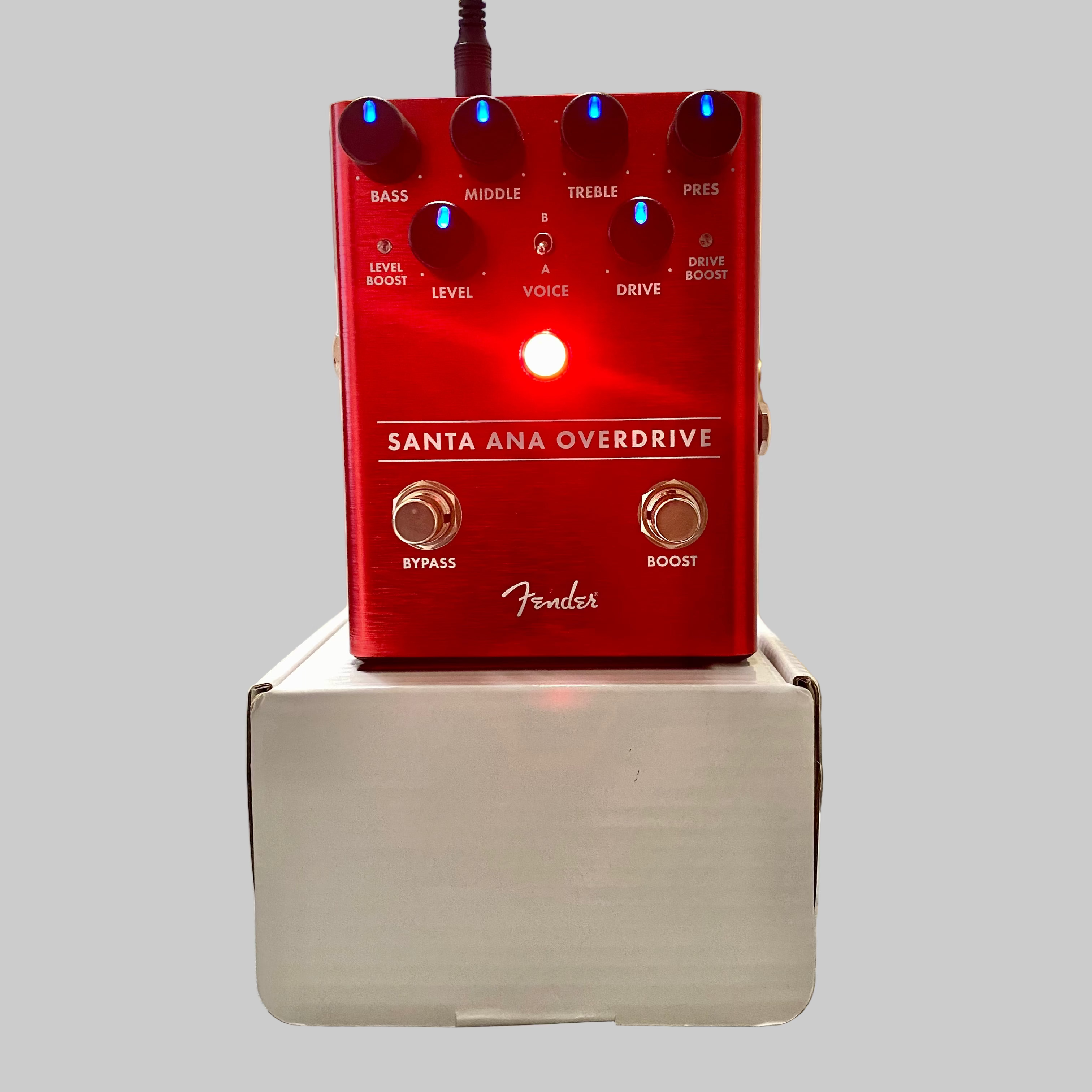Red Fender Santa Ana Overdrive pedal on a box with a blurred indoor background