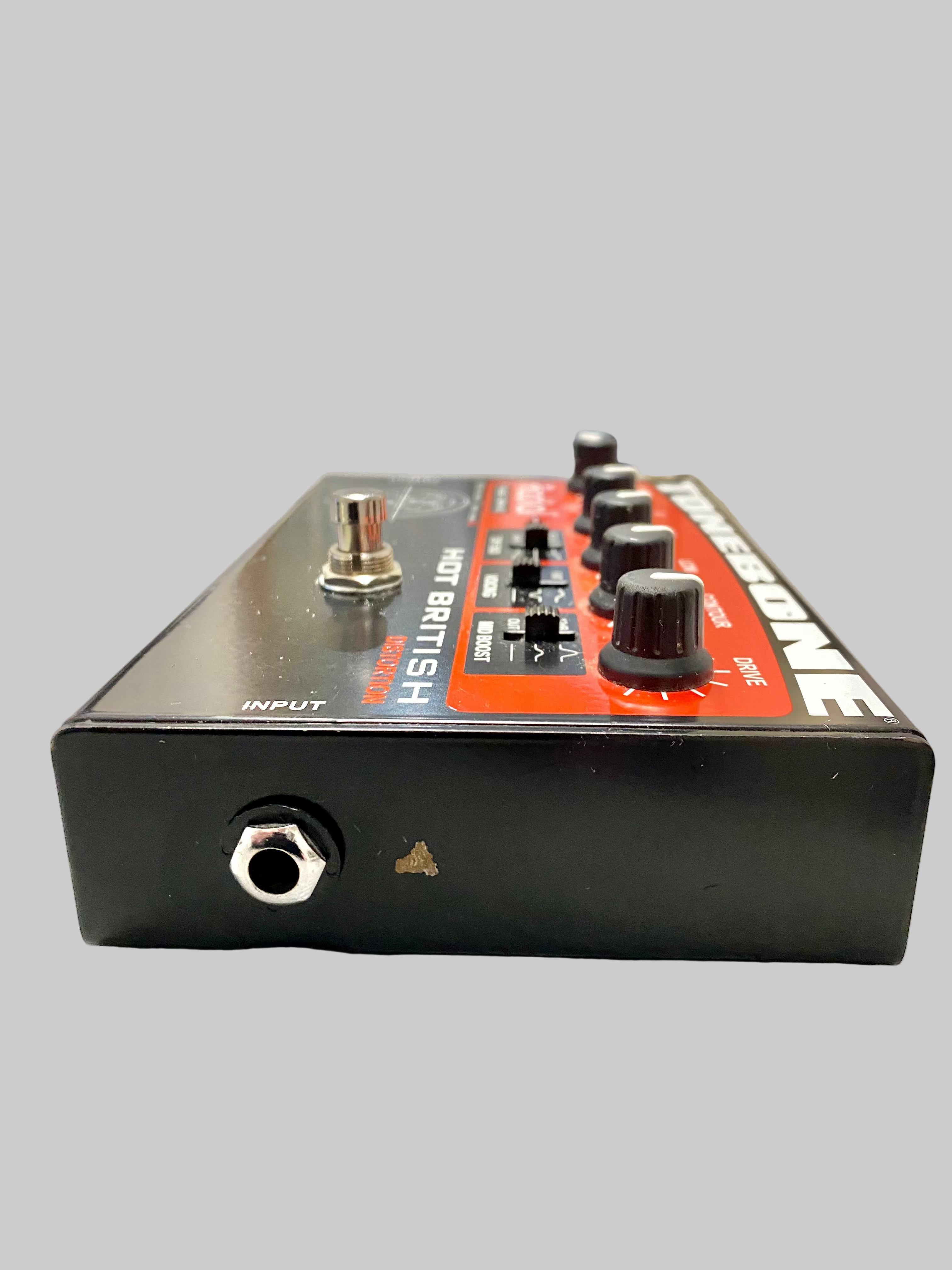 Guitar effects pedal on a table with a blurred room background