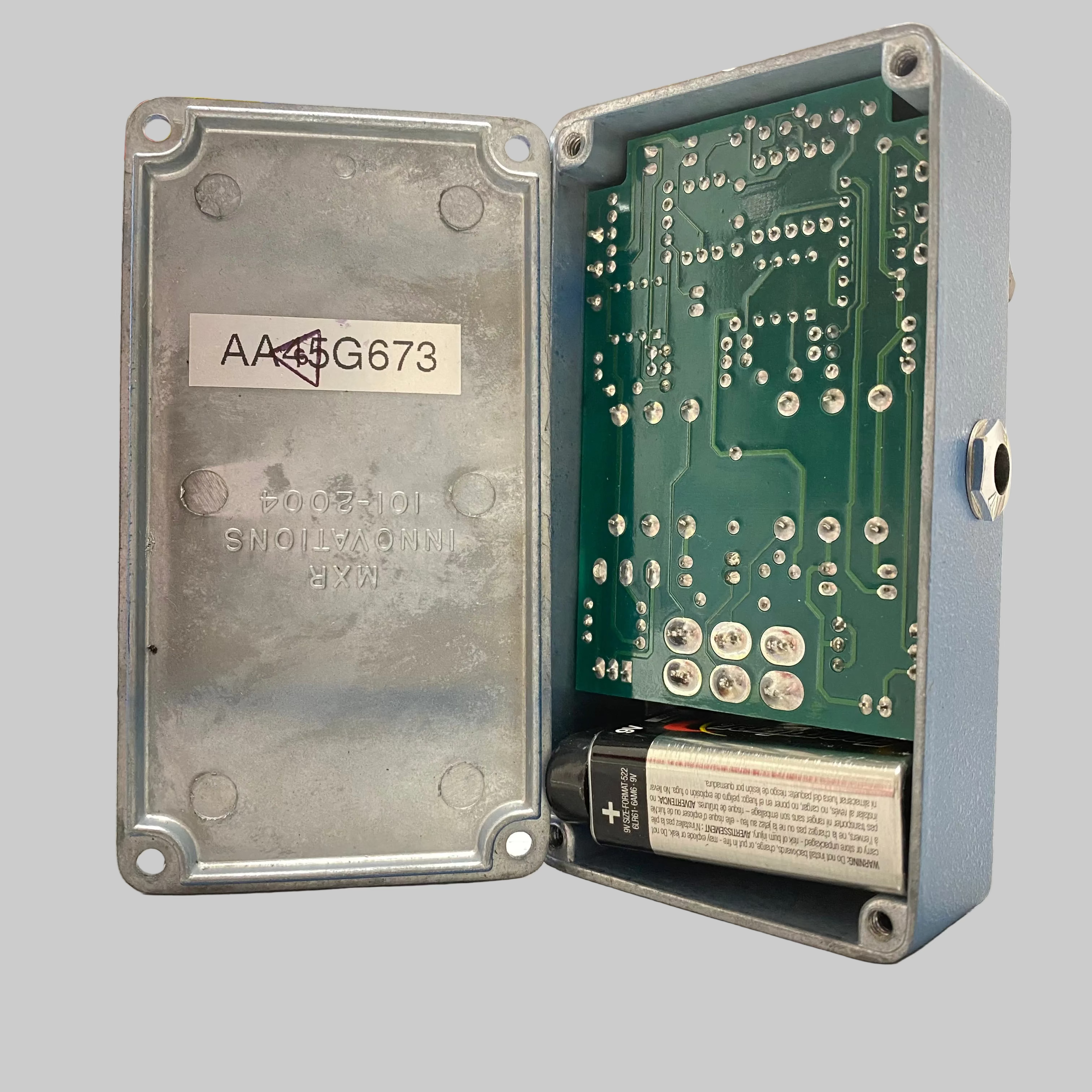 Electronic device with open cover showing circuit board and battery on a desk.