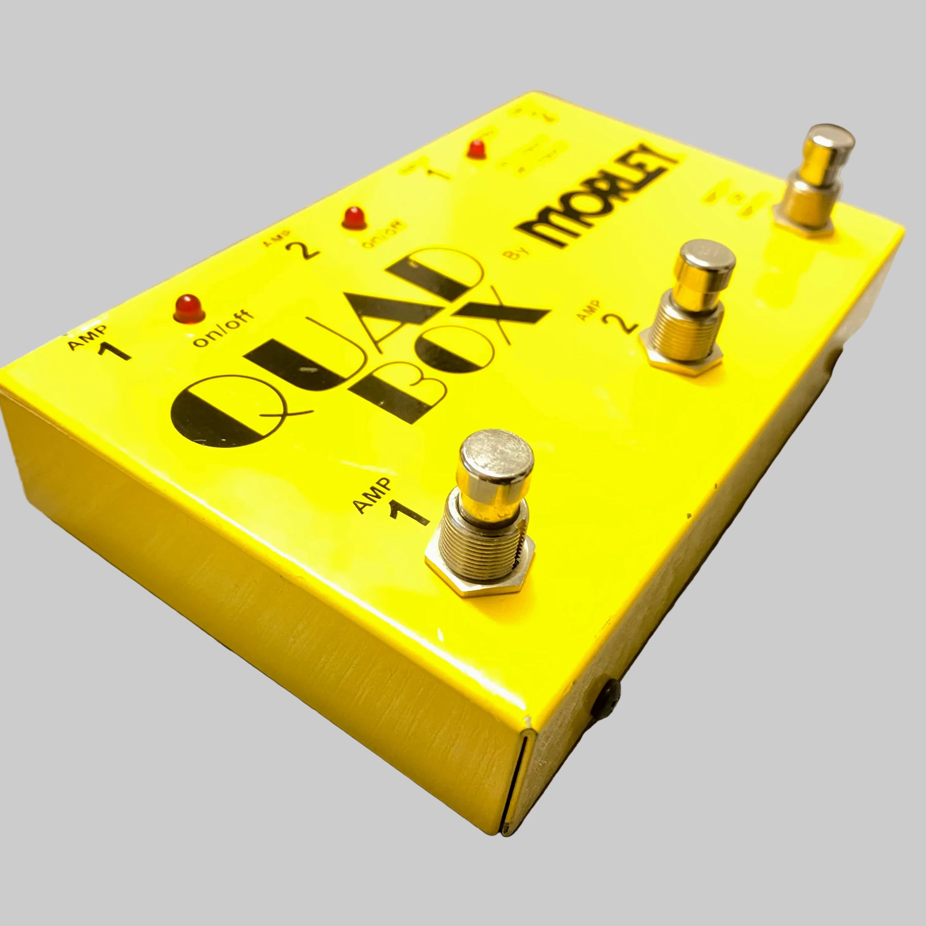 Yellow guitar effects pedal with 'Quad Box' branding on a wooden surface