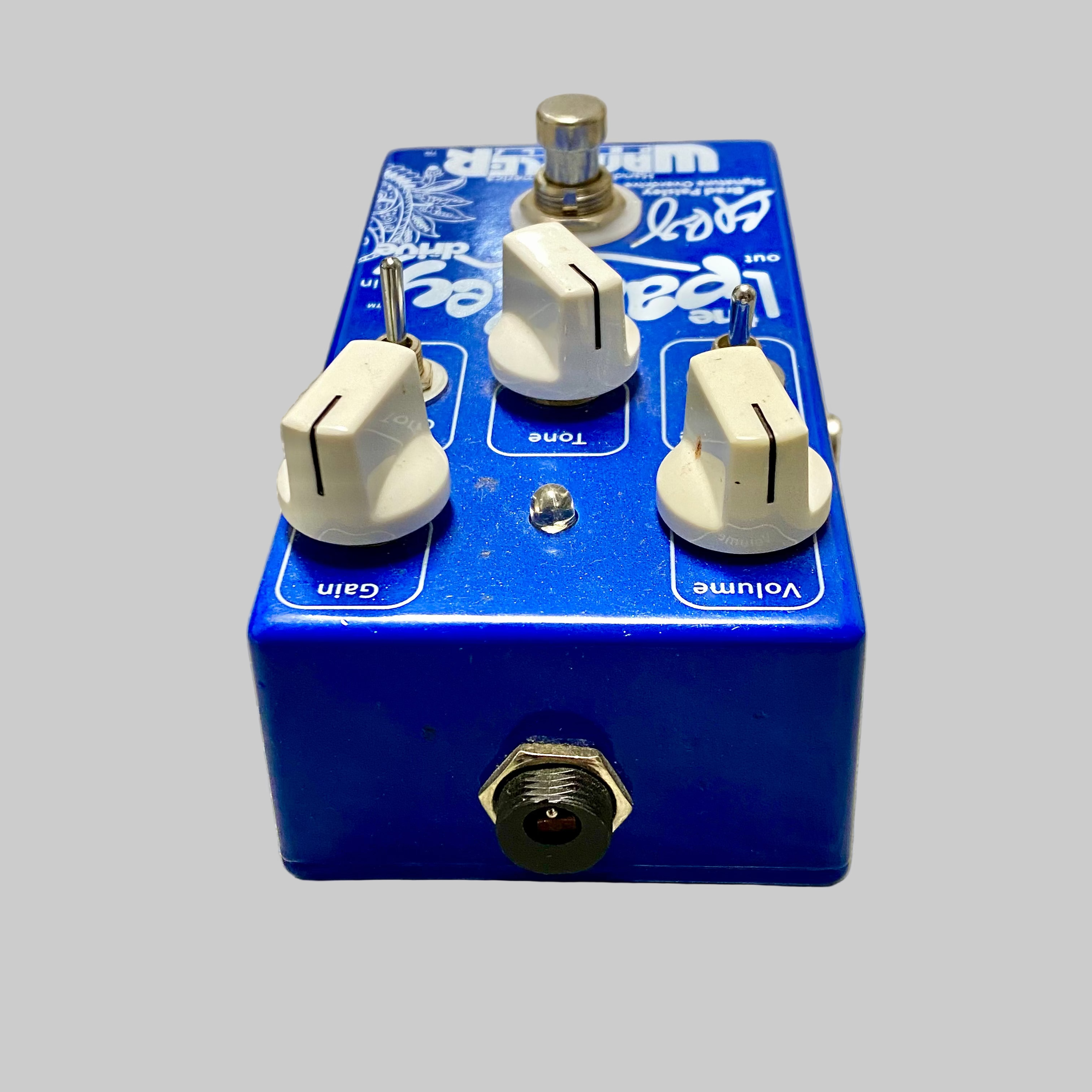 Blue guitar effects pedal with three knobs on a wooden surface