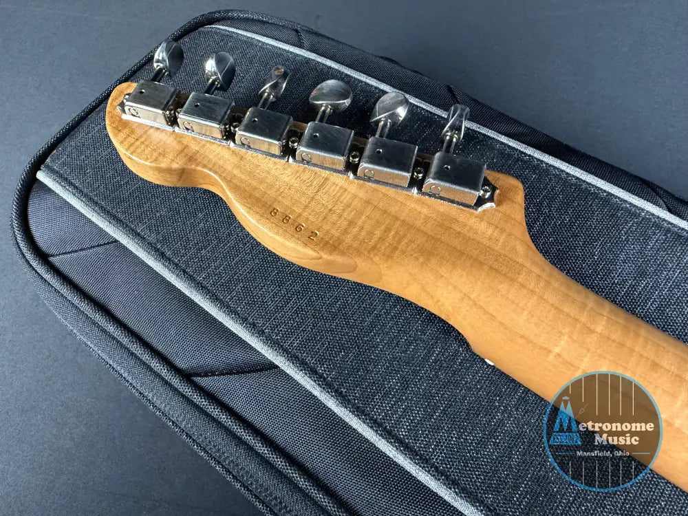 Close-up of a guitar's headstock with tuning pegs on a dark case.