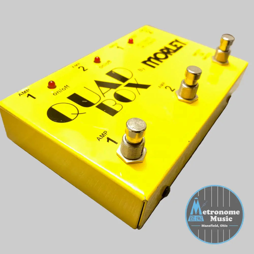 Yellow guitar effects pedal with 'Quad Box' branding on a wooden surface