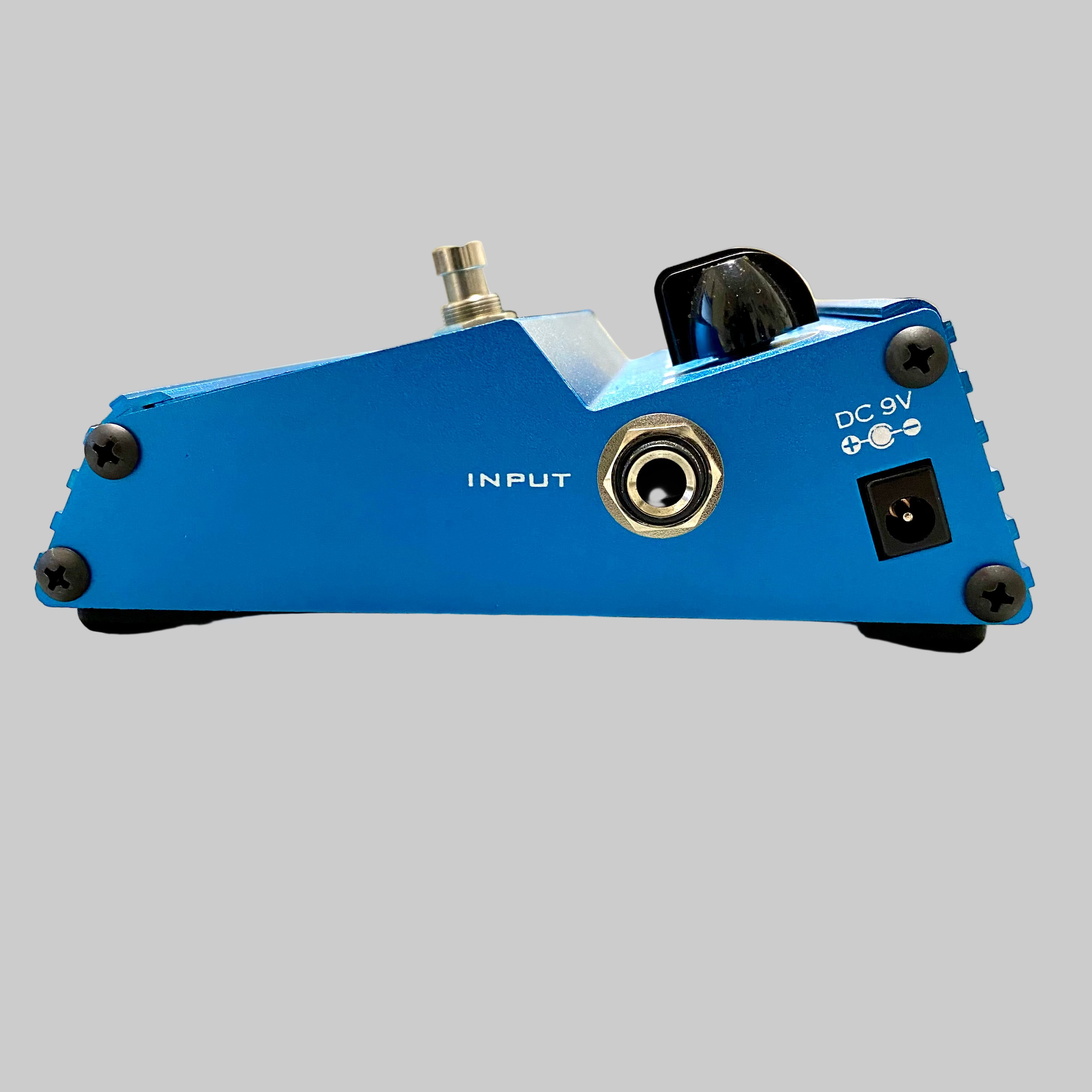 Blue guitar effects pedal on a wooden surface with a blurred indoor background