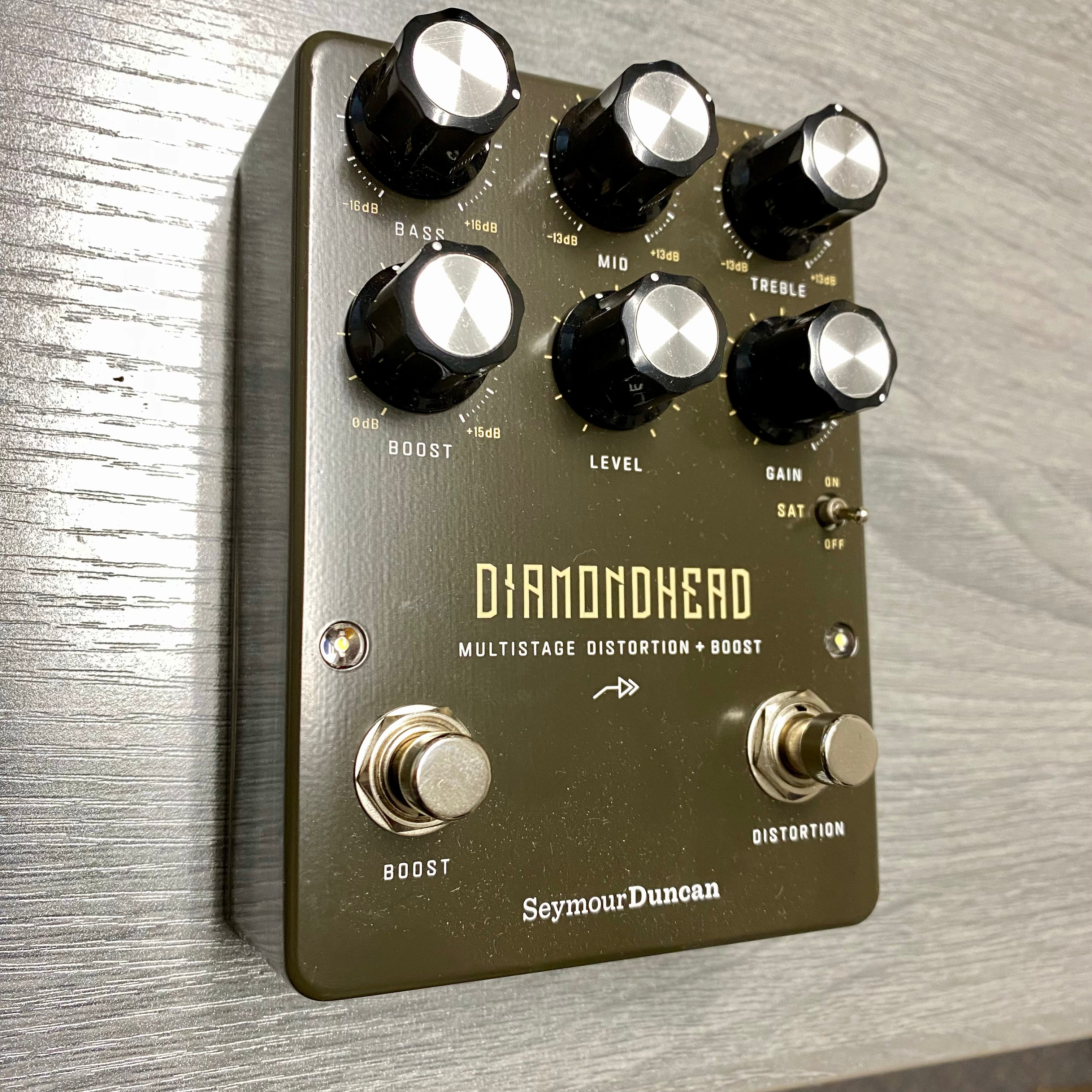 Guitar effects pedal with knobs and labels on a wooden surface