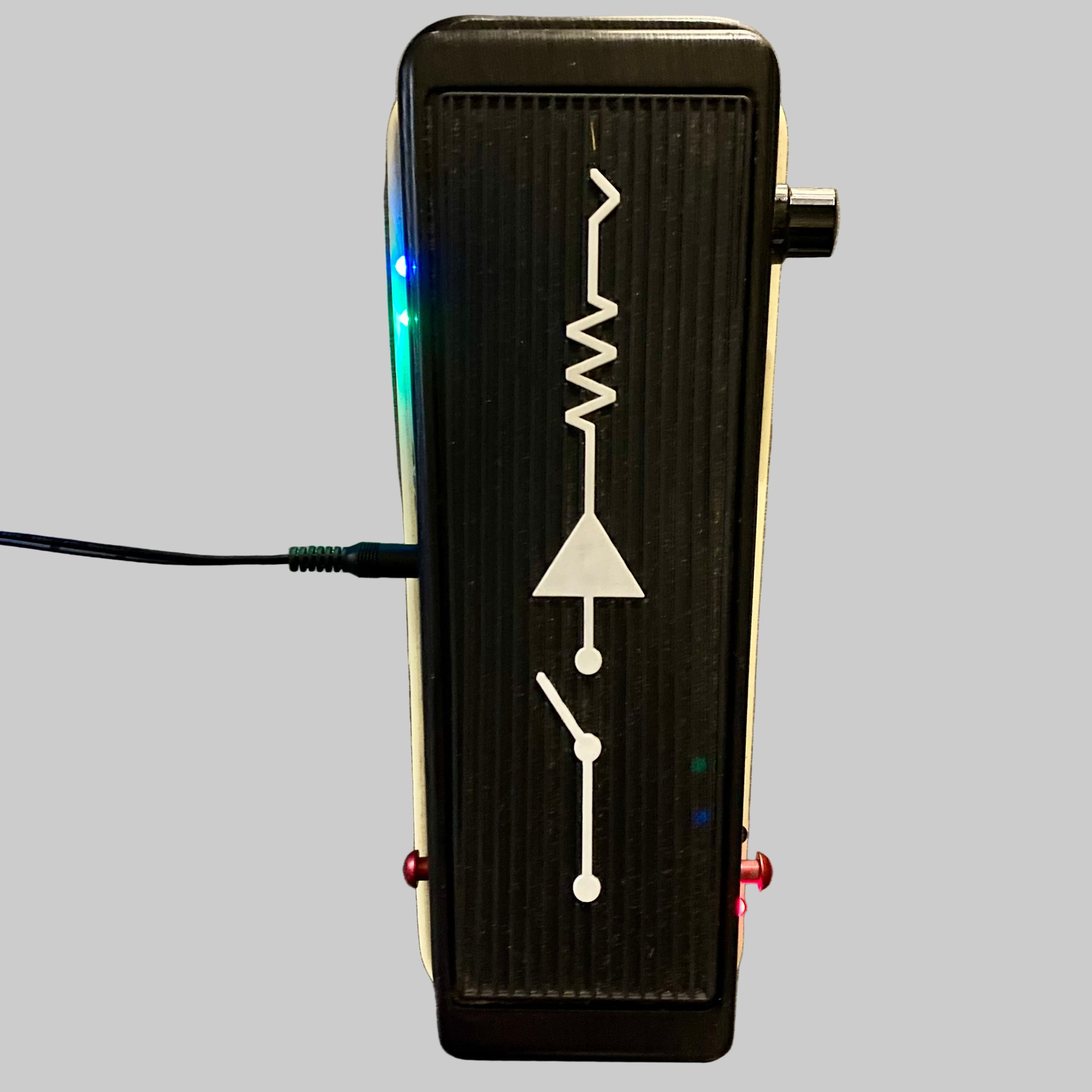 Black guitar effects pedal with white line design on a wooden surface
