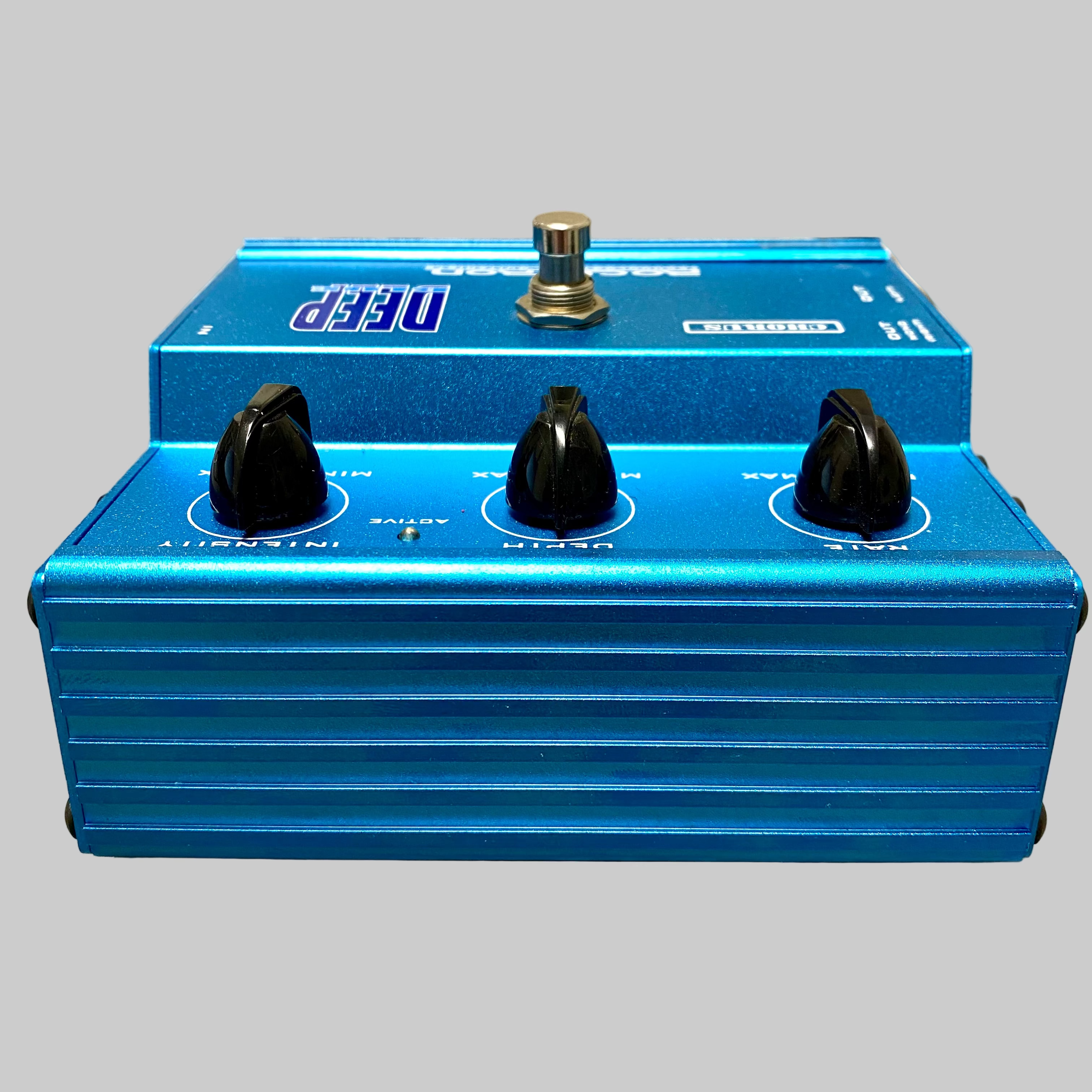 Blue guitar effects pedal with three knobs on a light gray surface.