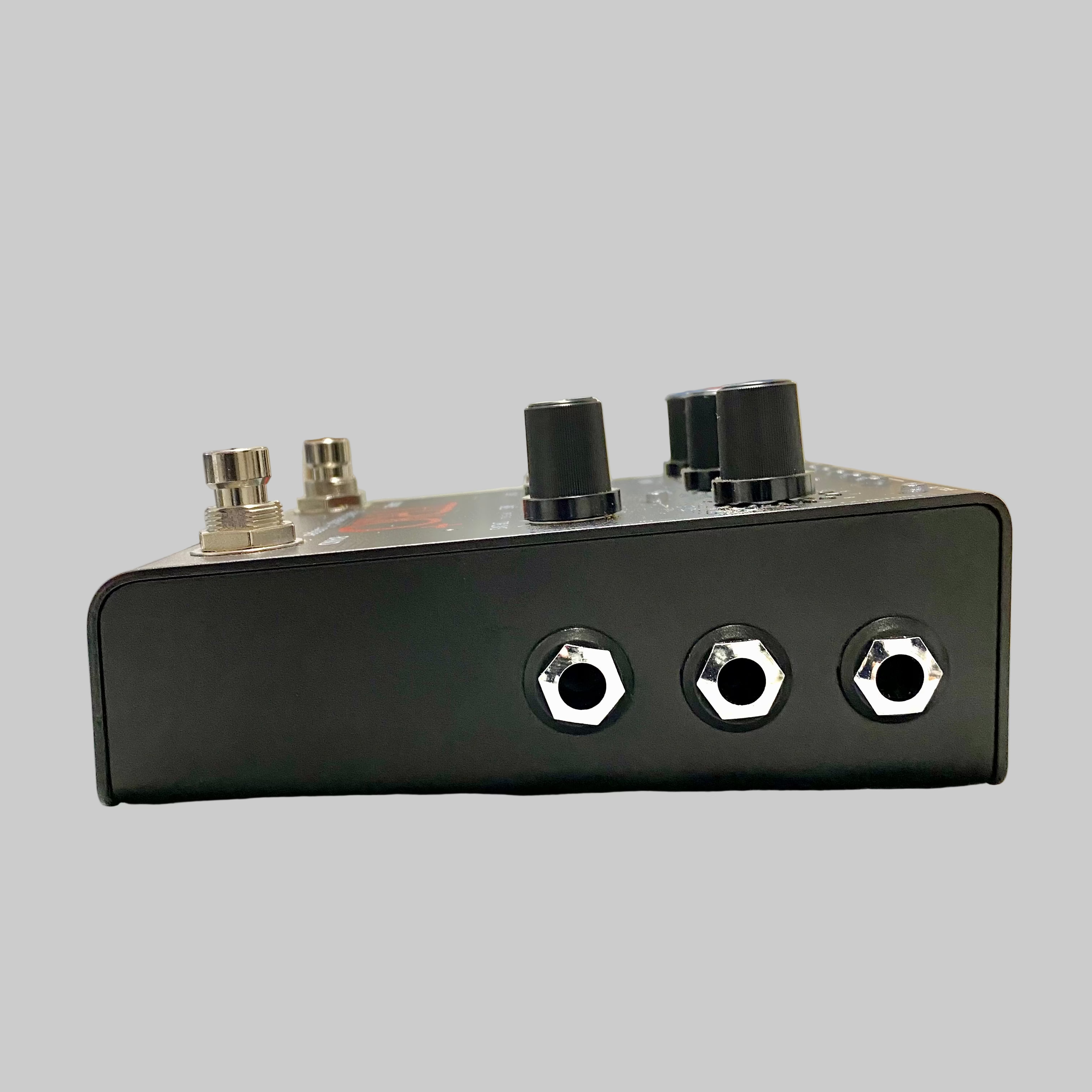 Black guitar effects pedal with knobs and jacks on a wooden surface