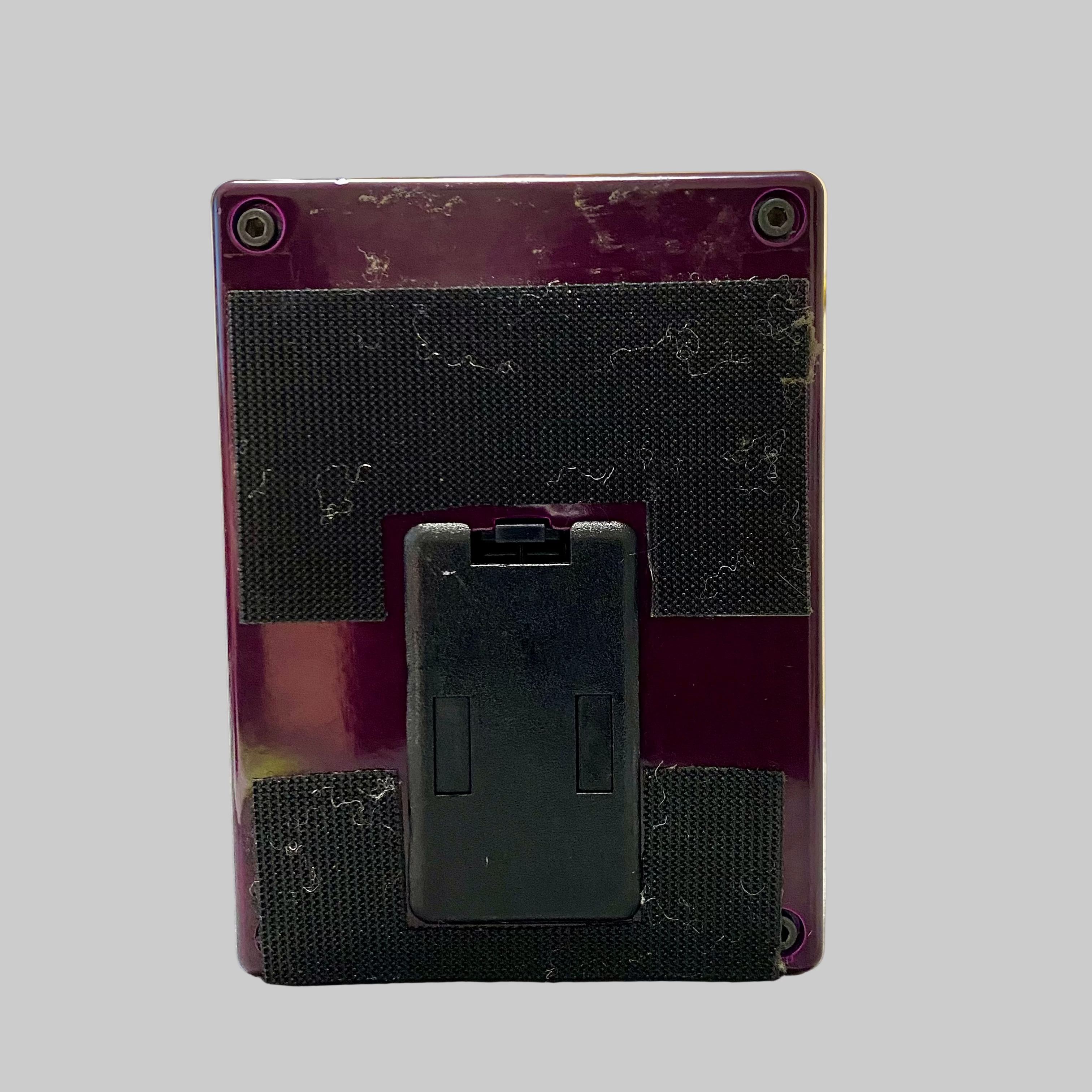 Back view of a purple electronic device on a table with a blurred indoor background