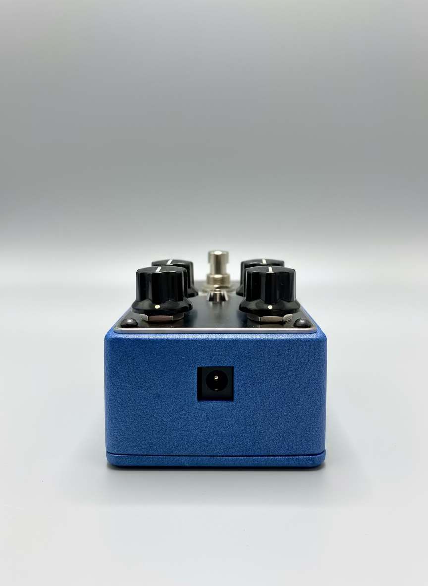 Blue guitar effects pedal with black knobs on a wooden surface