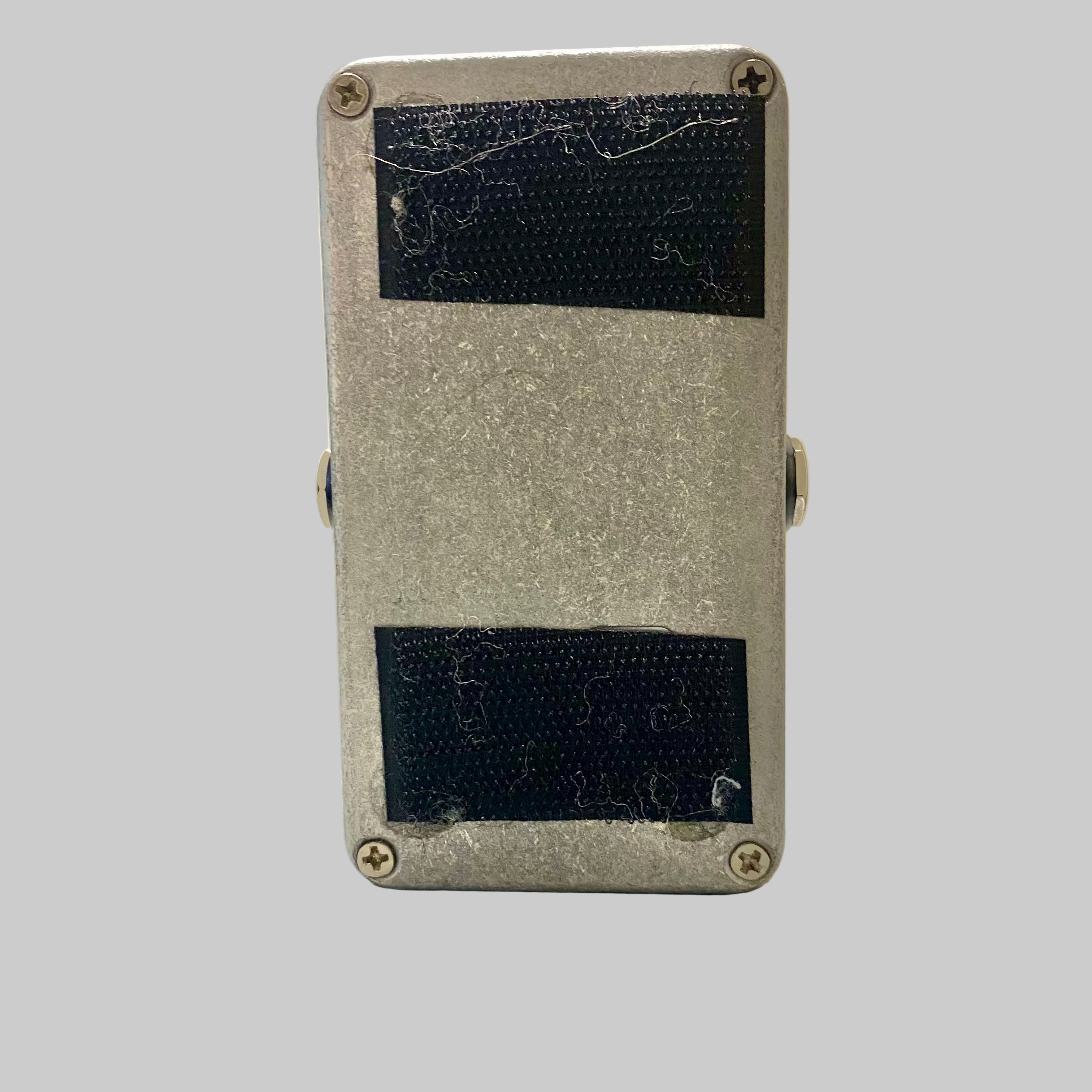 Small rectangular metal box with black patches on a wooden surface