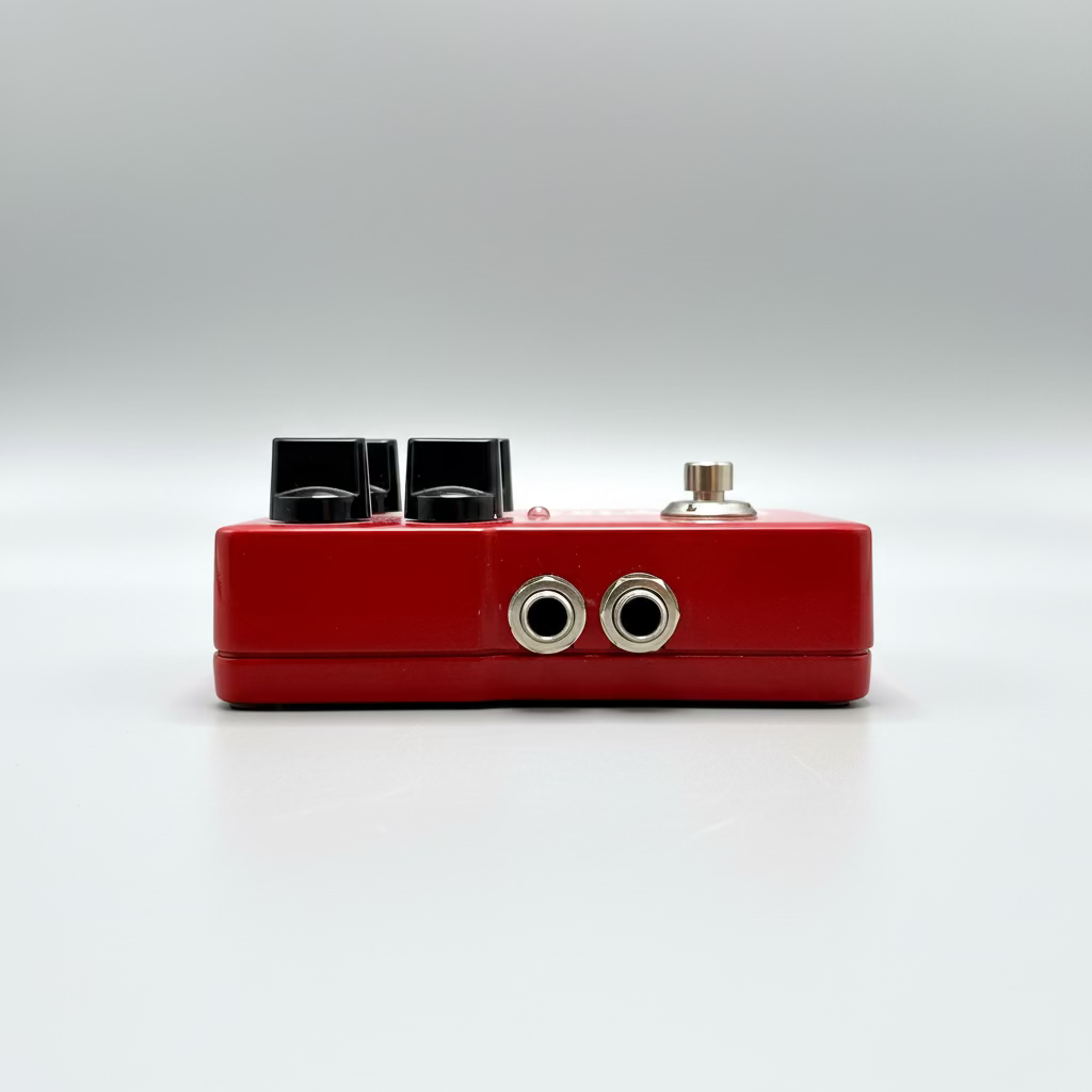 Red guitar effects pedal on a wooden surface with a blurred background