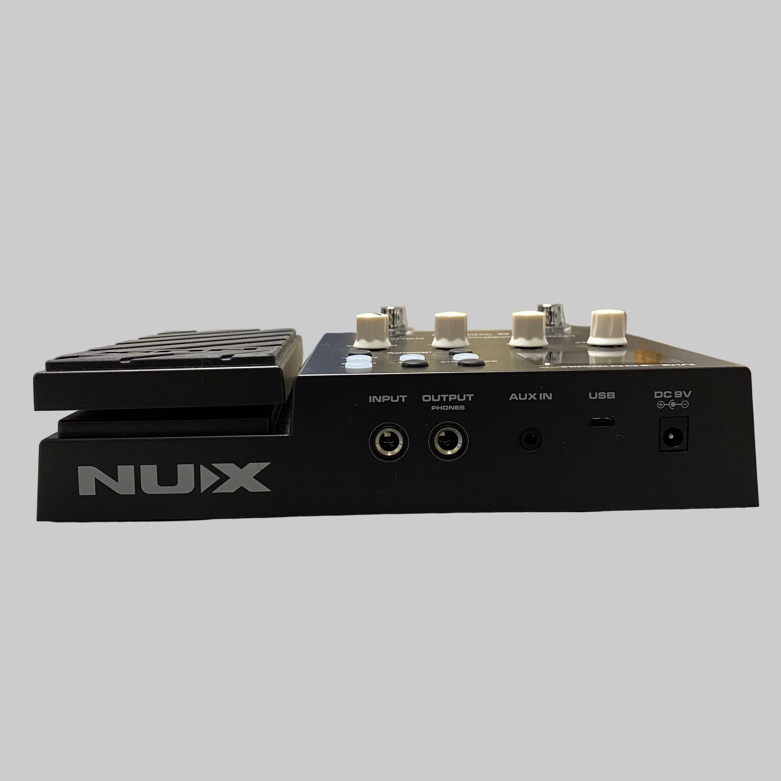 NUX audio device on a table with a guitar in the background