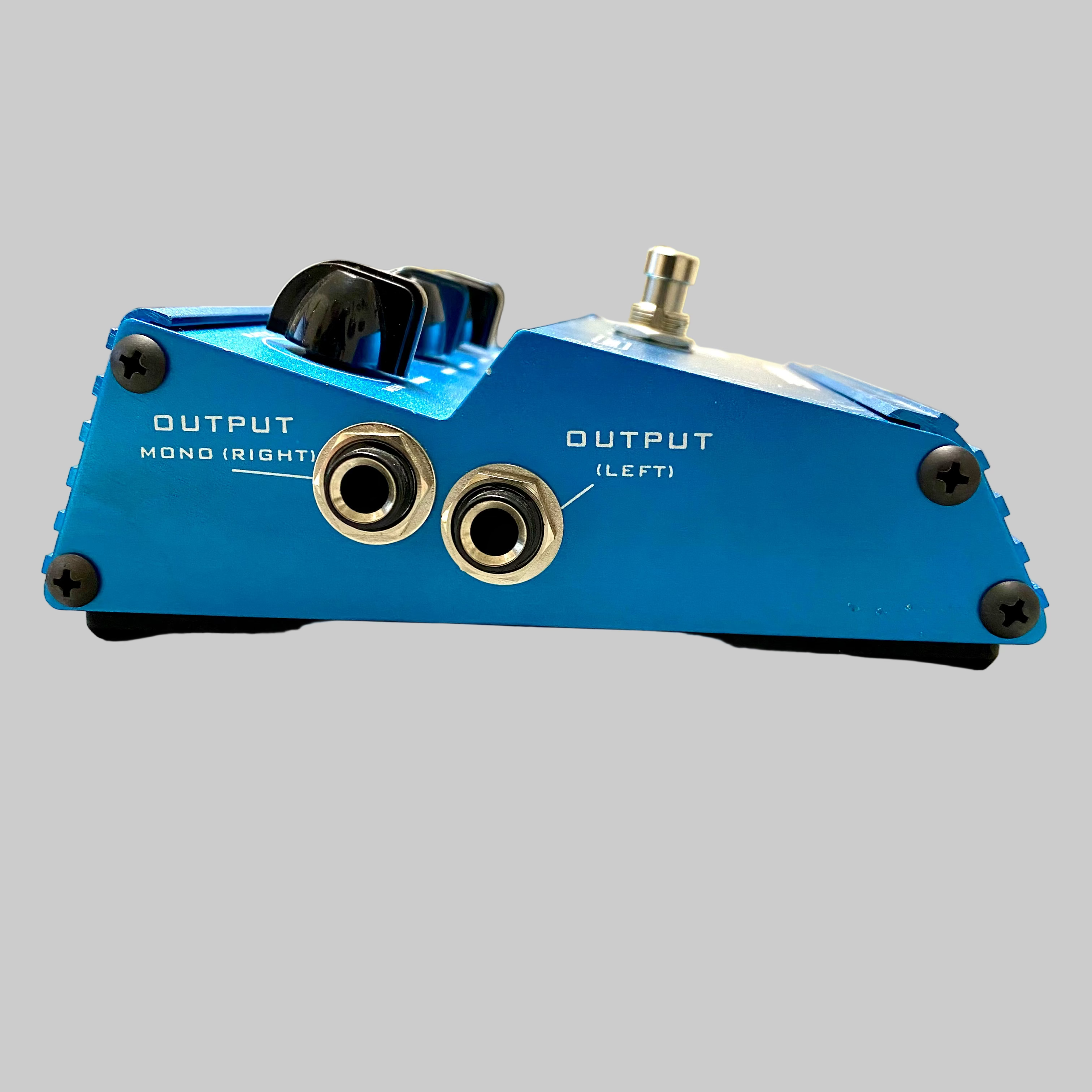 Blue guitar effects pedal with two output jacks on a light wooden floor.