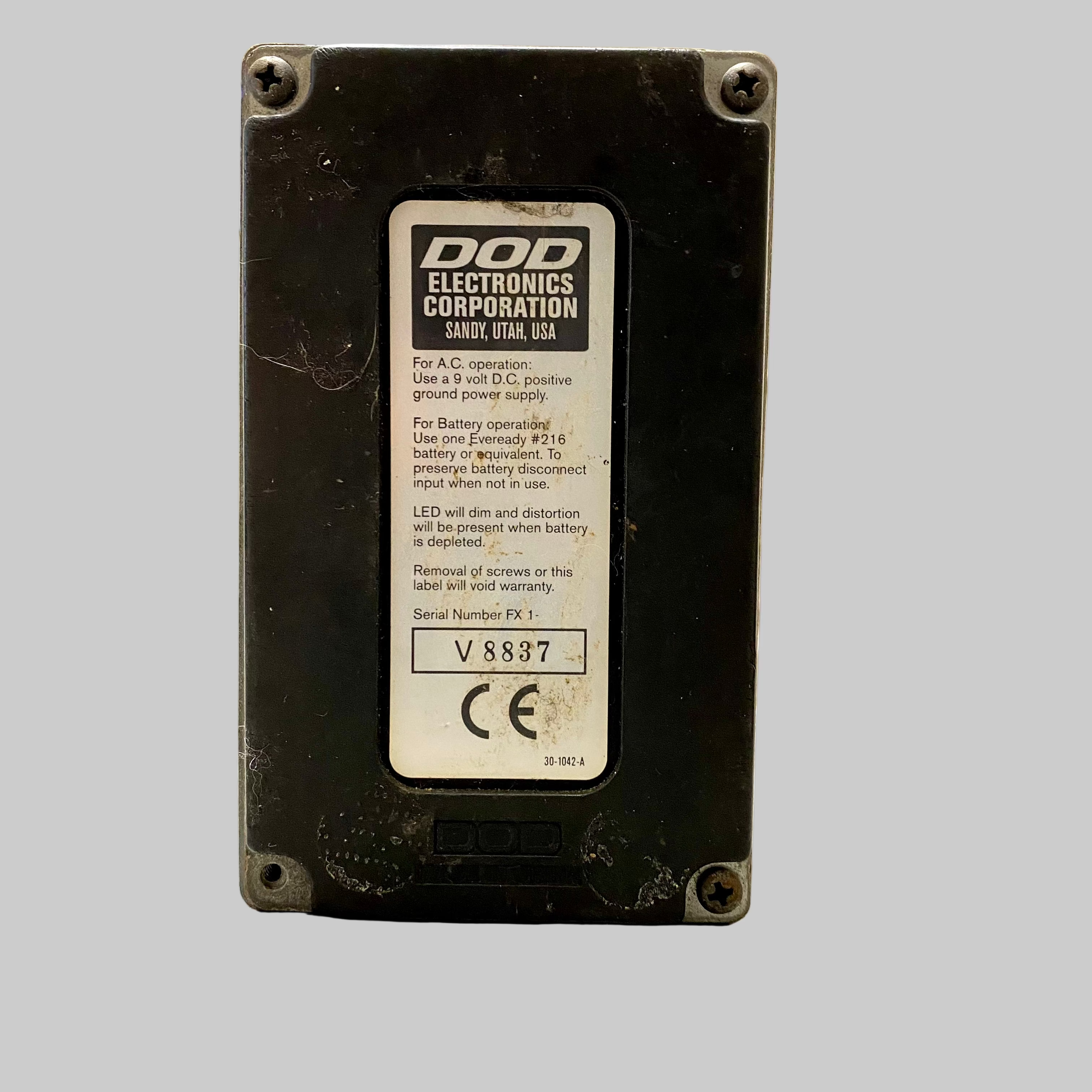Back of a black electronic device with DOD Electronics Corporation label on a light surface.
