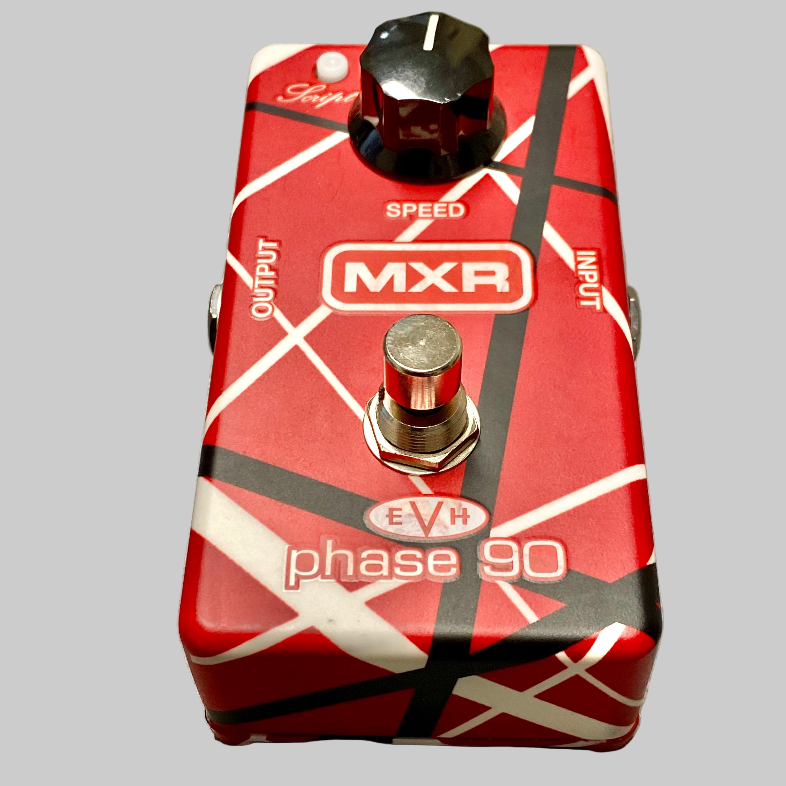 Red guitar effects pedal with 'MXR' and 'EVR' branding on a wooden surface