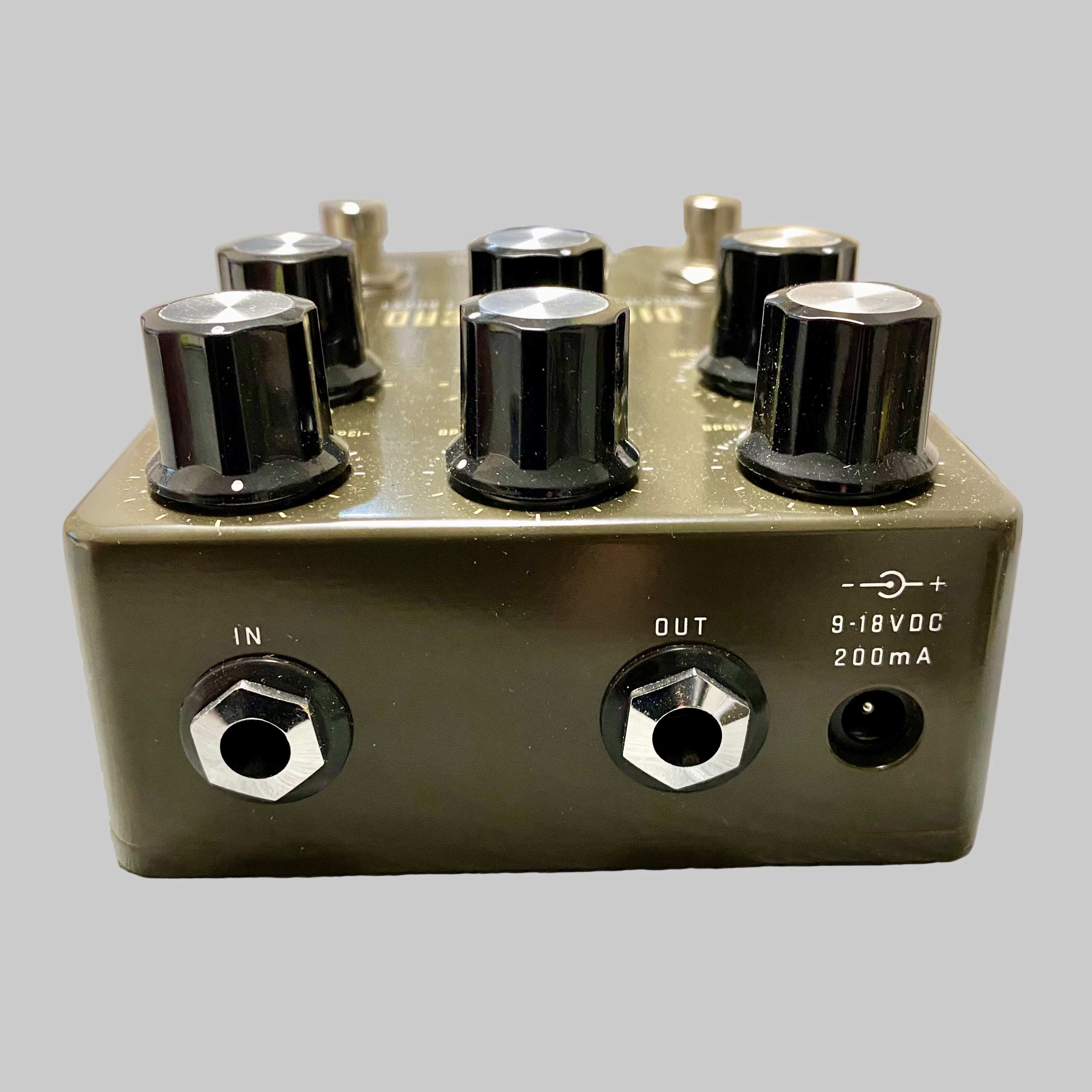 Audio effects pedal with knobs and input/output jacks on a wooden surface.