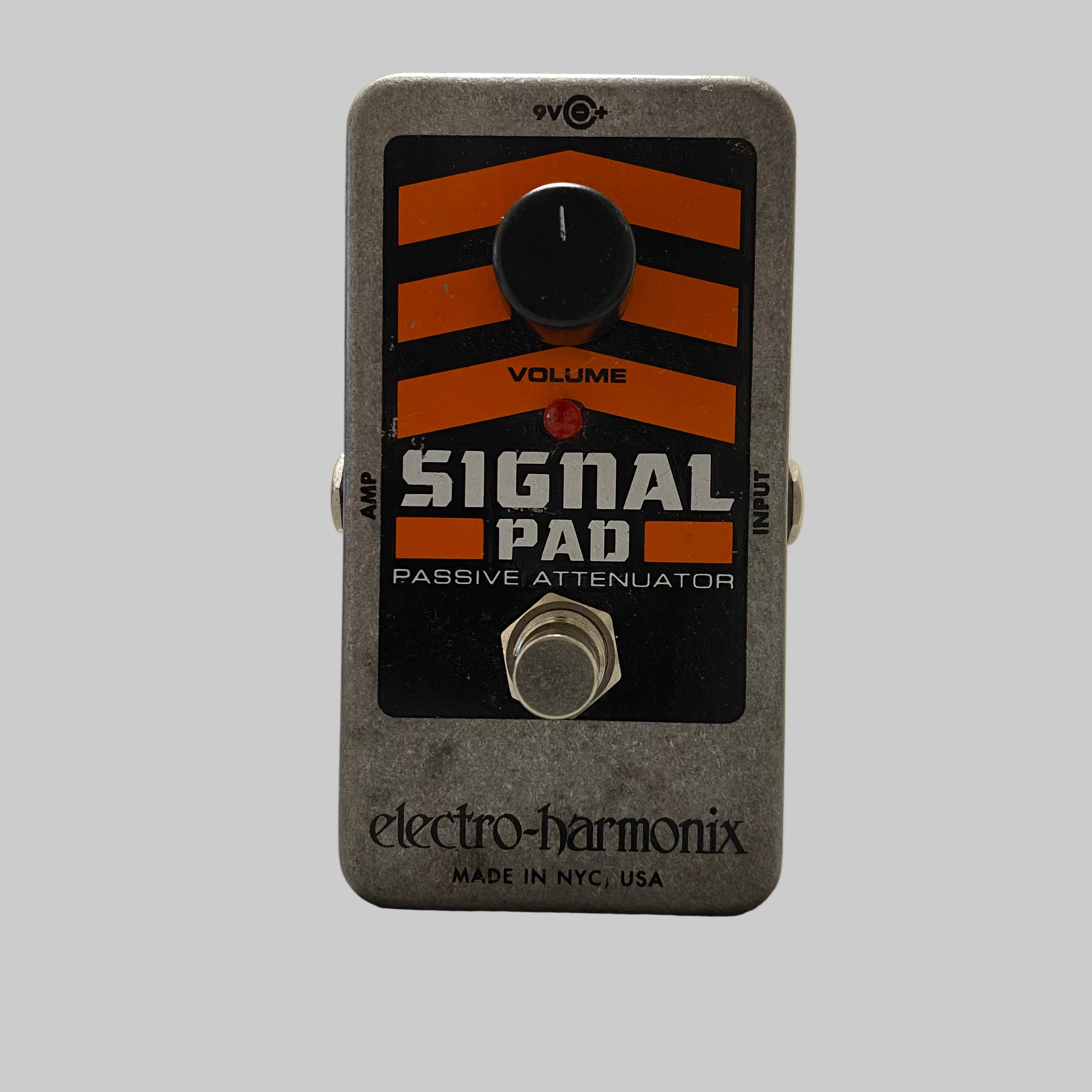 Electro-Harmonix Signal Pad passive attenuator pedal on a table with a blurred indoor background