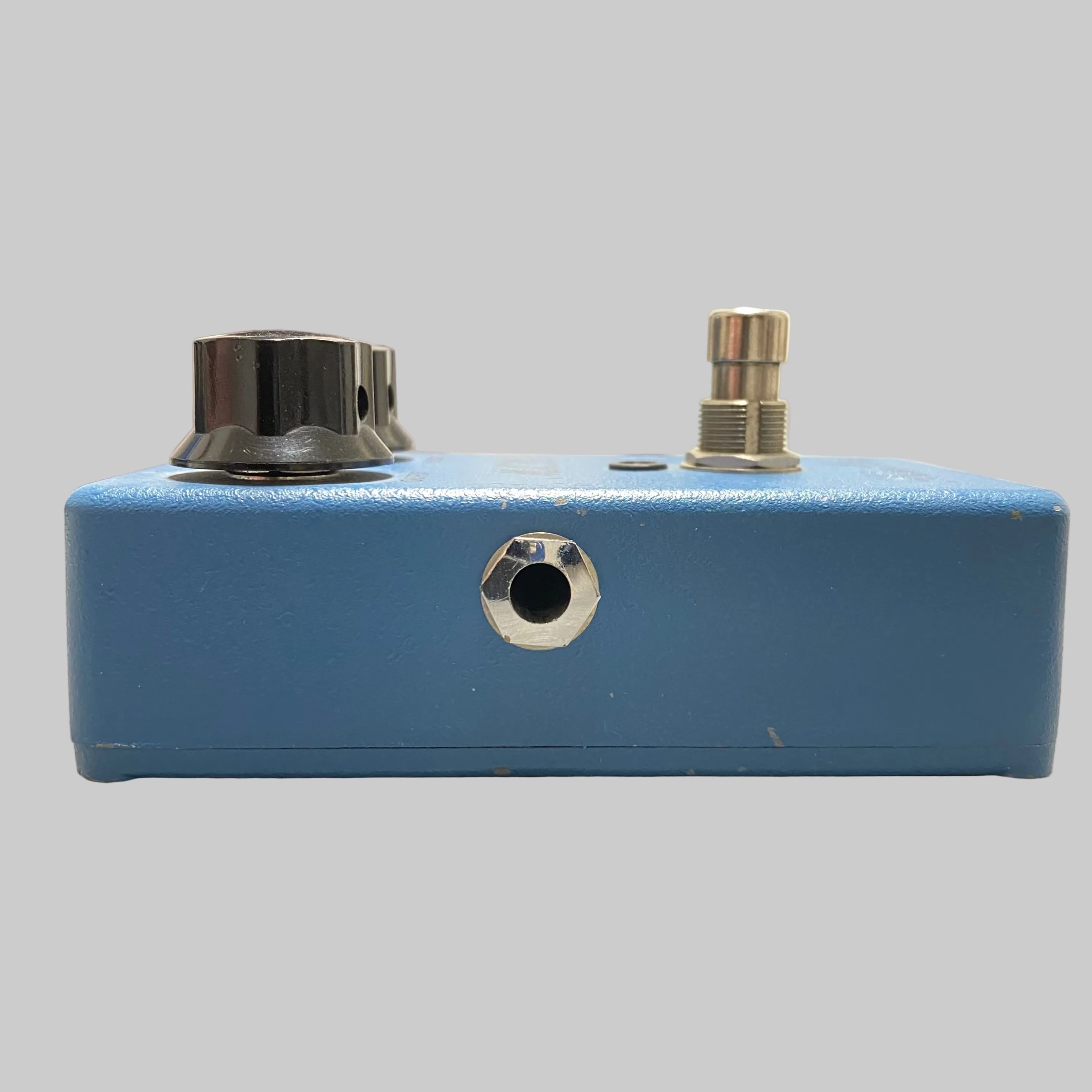 Blue guitar effects pedal on a table with a blurred background