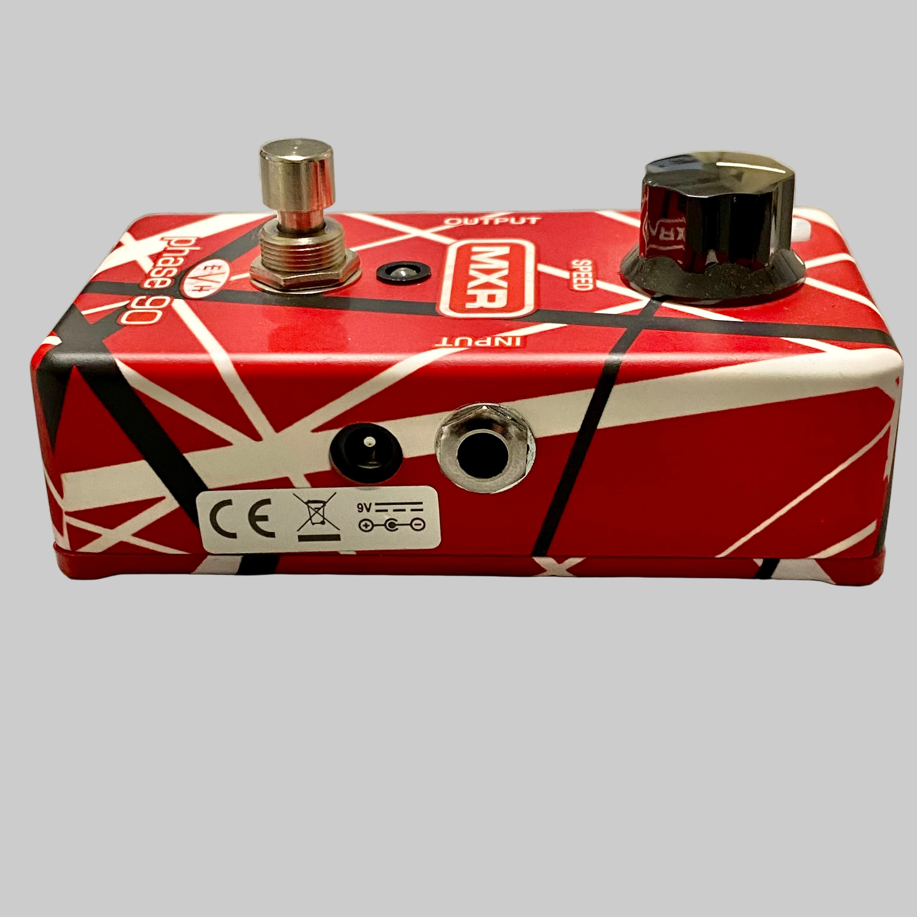 Red and black guitar effects pedal on a wooden surface