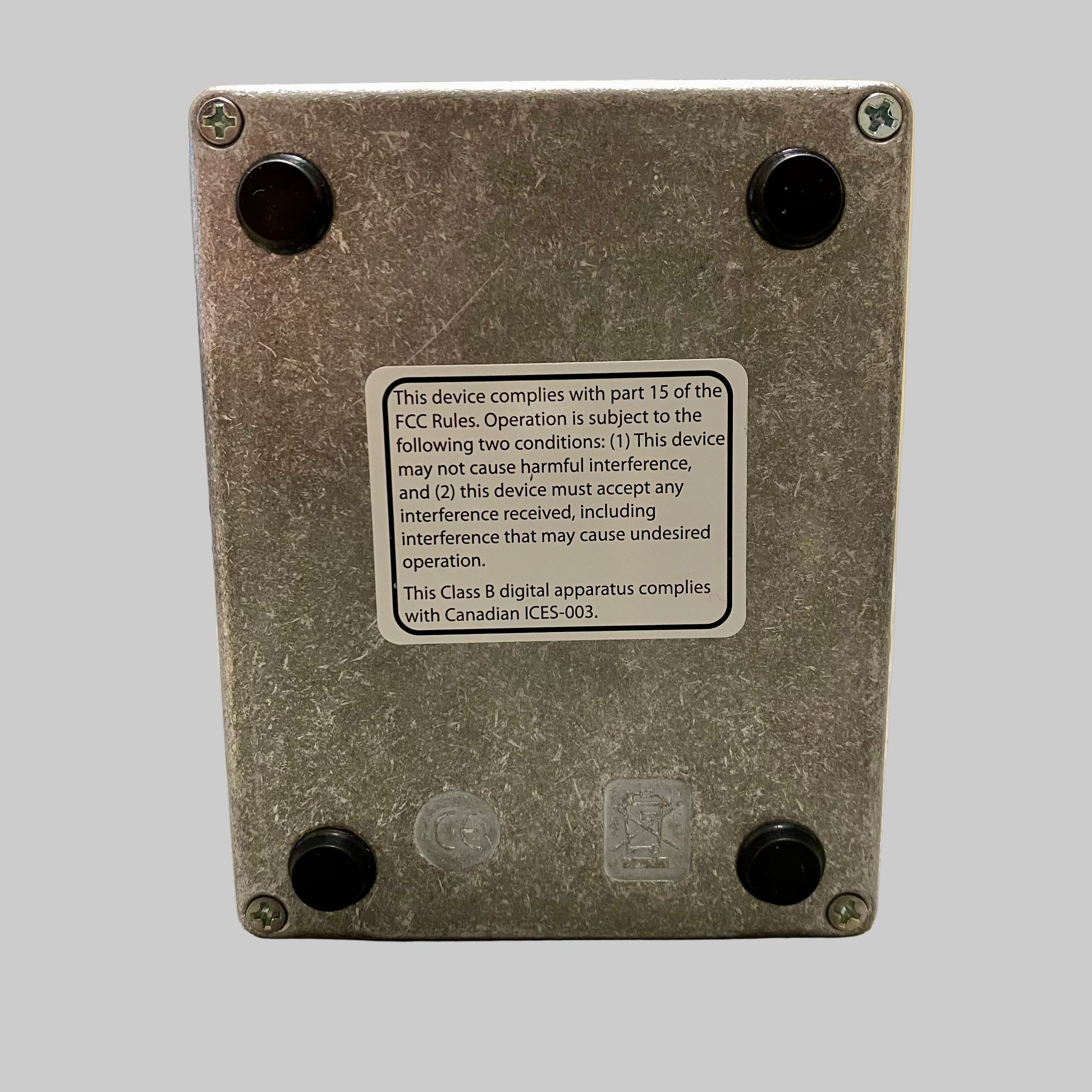 Back view of a metallic device with FCC compliance label on a wooden surface