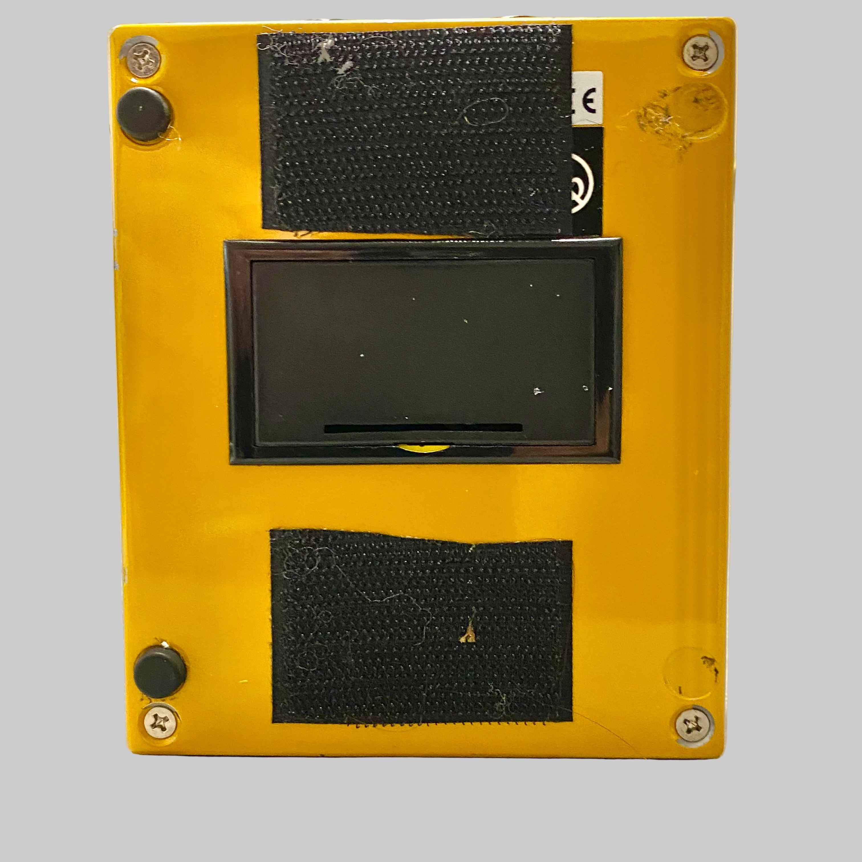 Yellow rectangular device with a black screen on a wooden surface