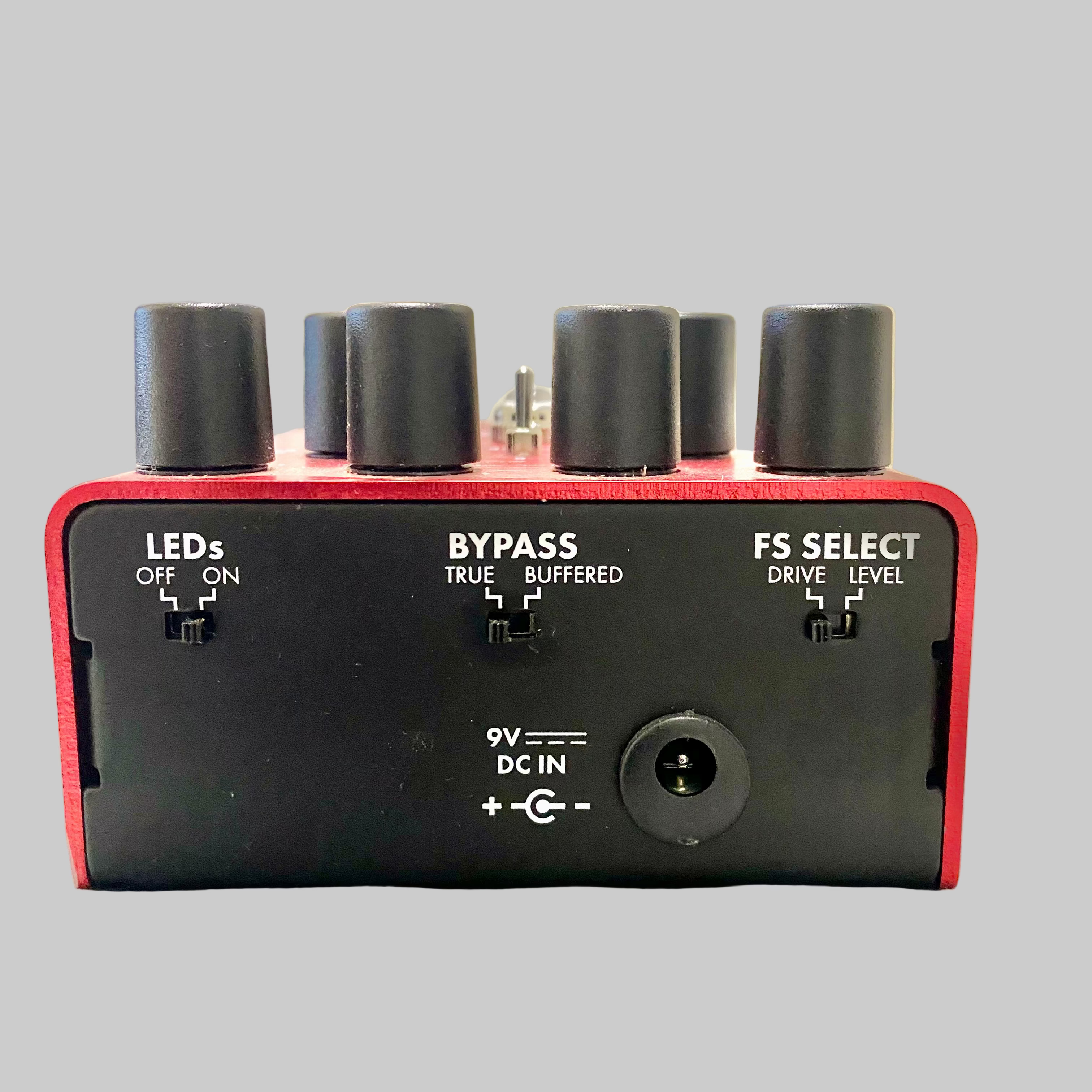 Red and black electronic device with various controls on a reflective surface.