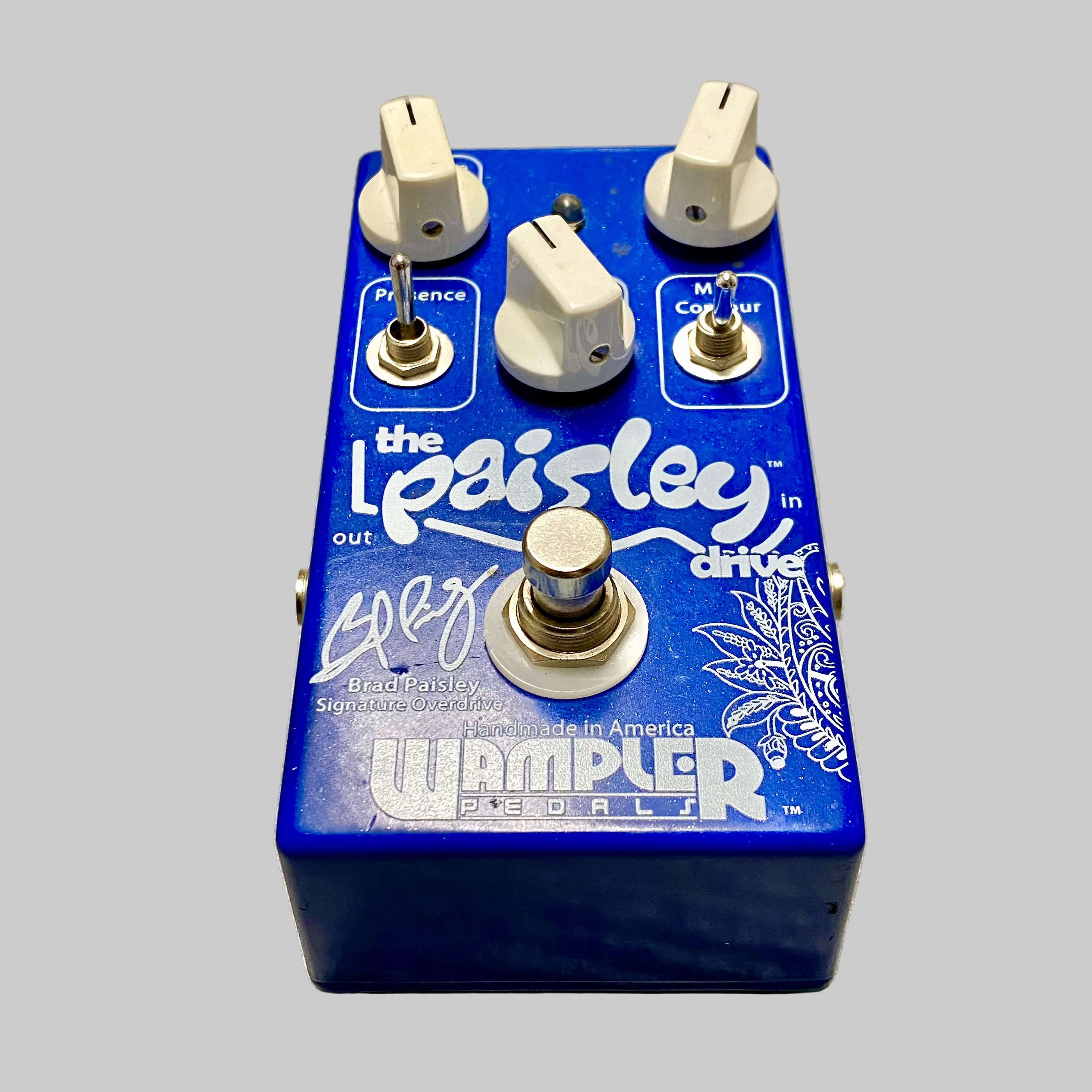 Blue guitar effects pedal with 'Brad Paisley' branding on a wooden surface
