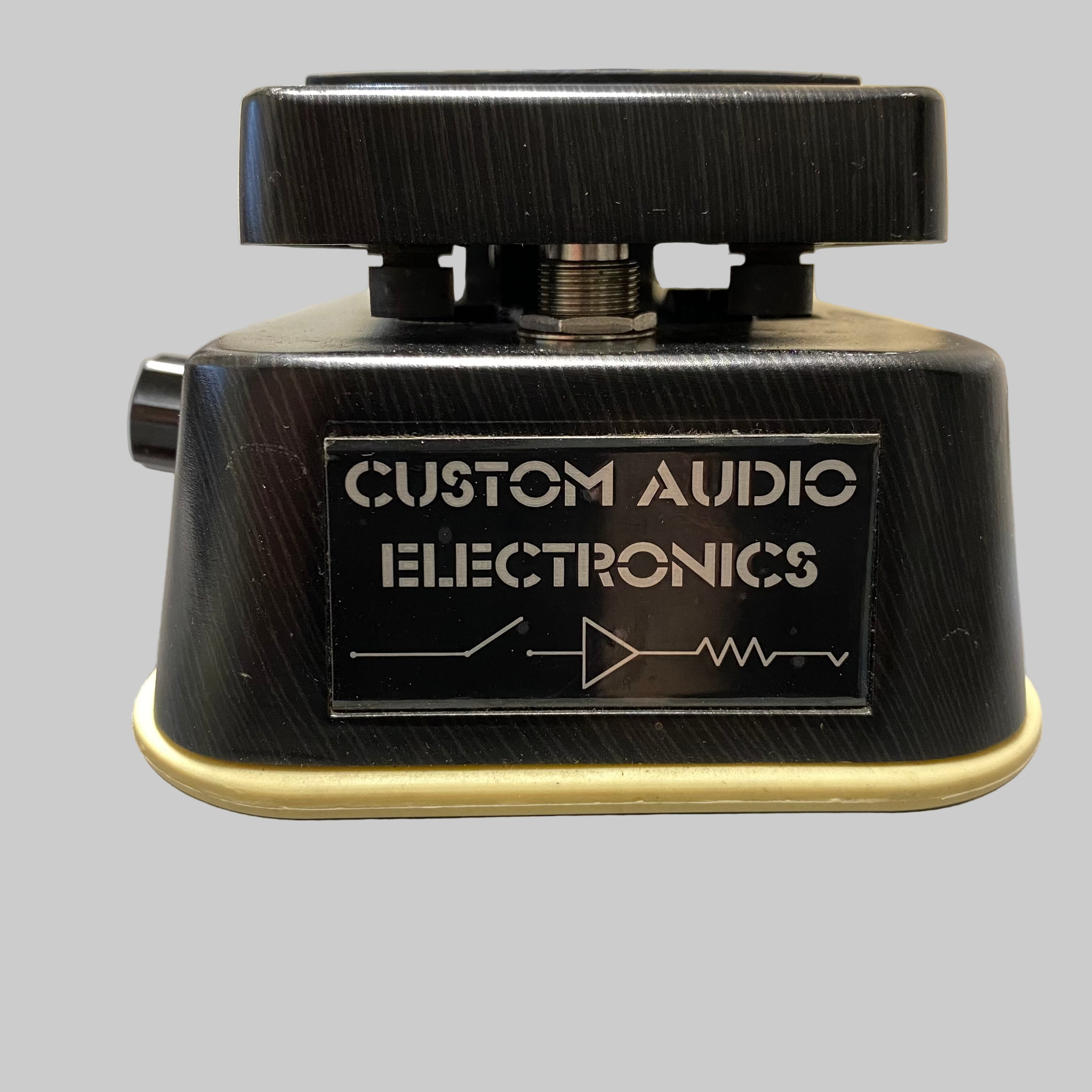 Black audio pedal with 'Custom Audio Electronics' branding on a gray surface.
