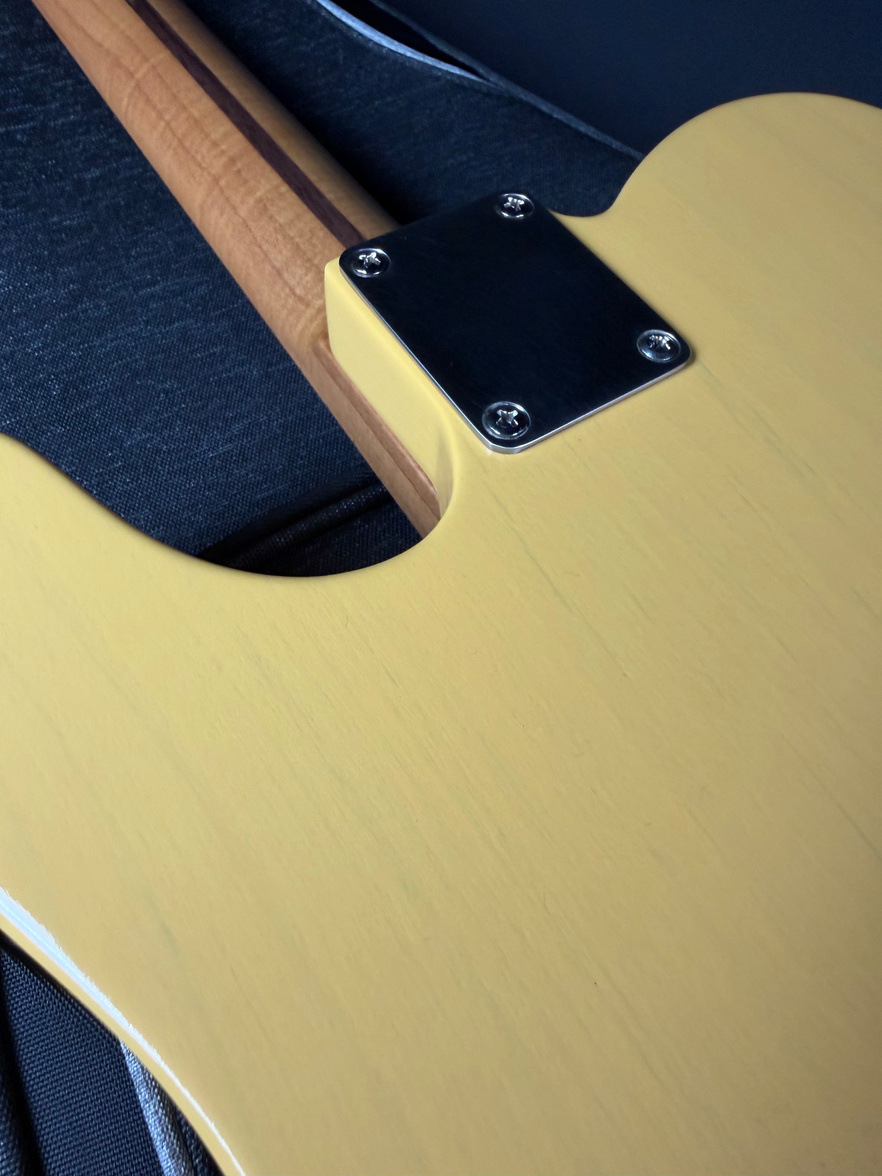 Close-up of a guitar with a focus on the body and neck joint.