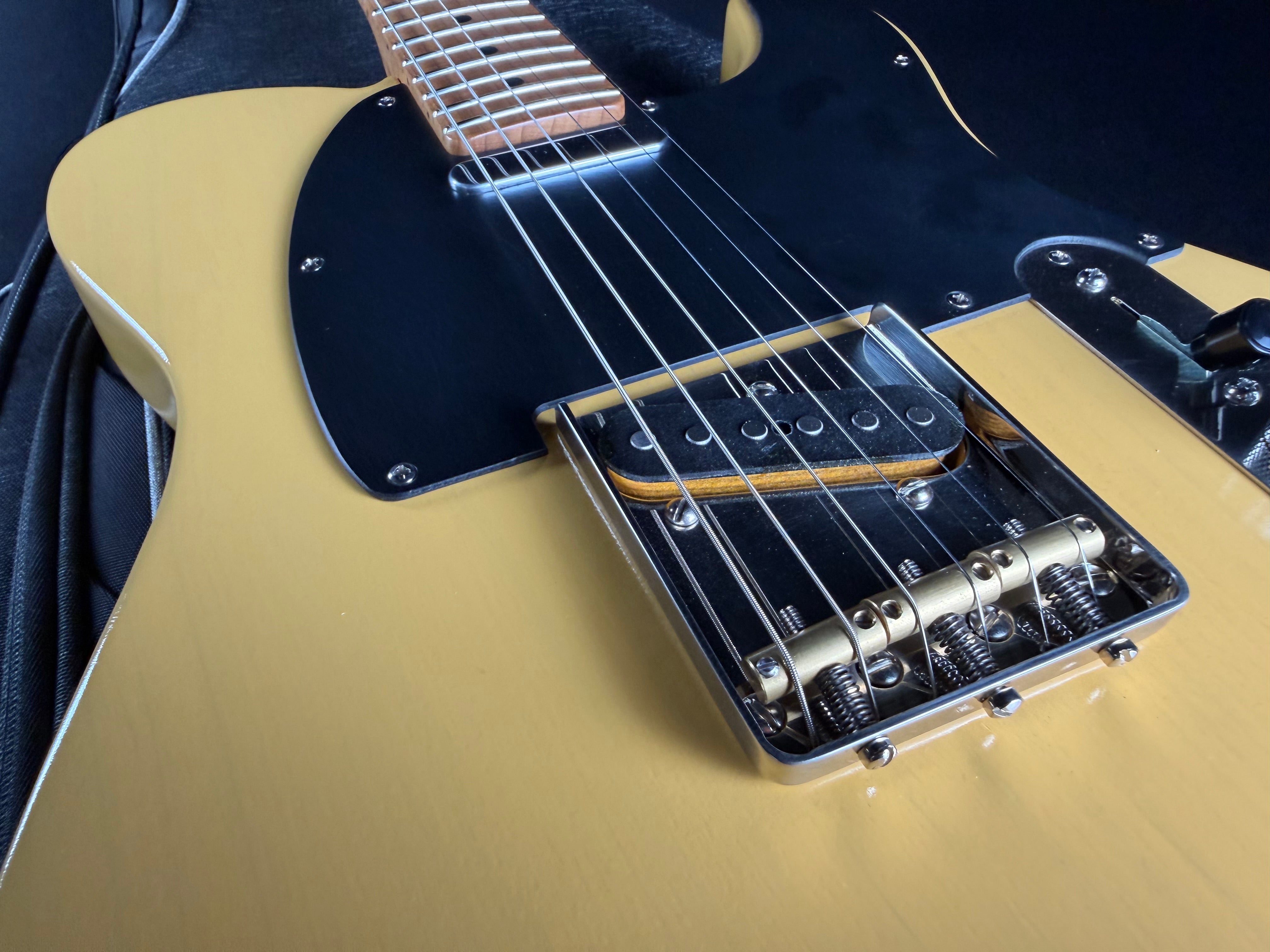Close-up of a guitar's neck and bridge on a dark background
