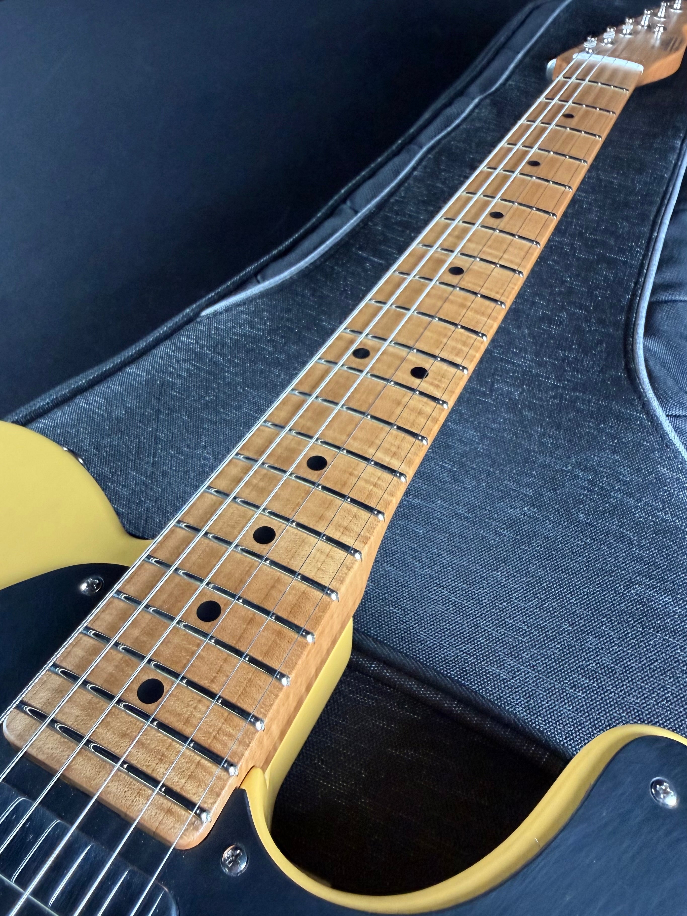 Close-up of a guitar neck and body against a blue case background