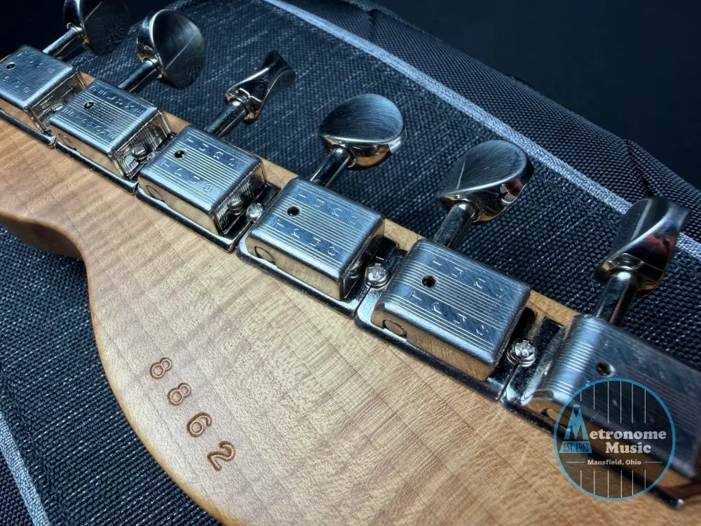 Close-up of a guitar's tuning pegs with a wooden neck and 'True Tune' branding.
