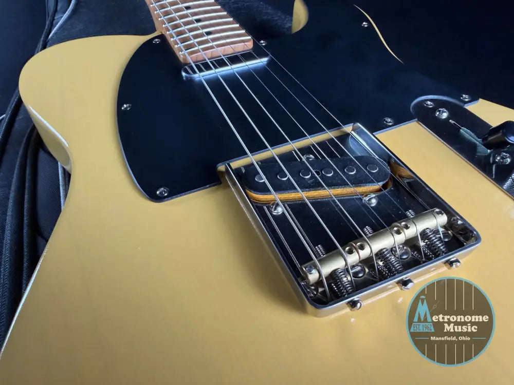 Close-up of a guitar's neck and bridge on a dark background