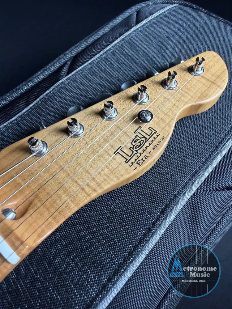 Close-up of a guitar headstock with 'LSL' branding on a textured black background