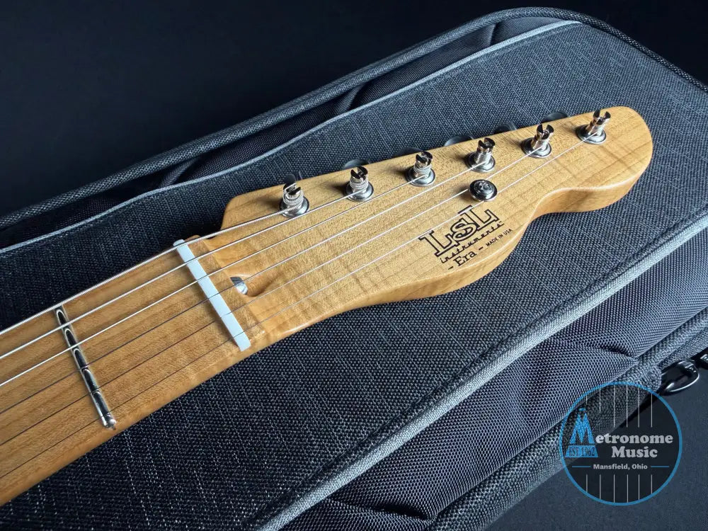 Guitar headstock with 'LSL' branding on a black guitar case.