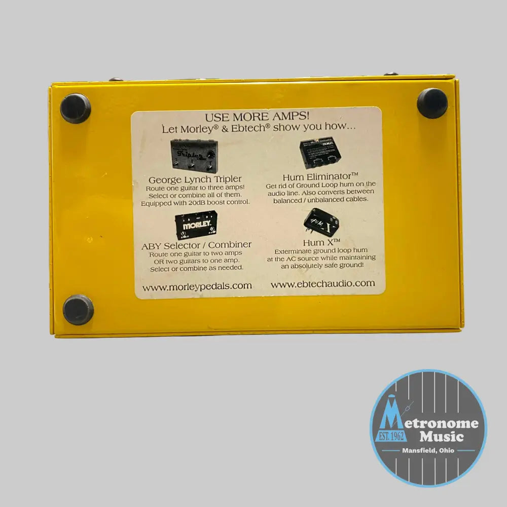 Yellow guitar effects pedal with text on a desk